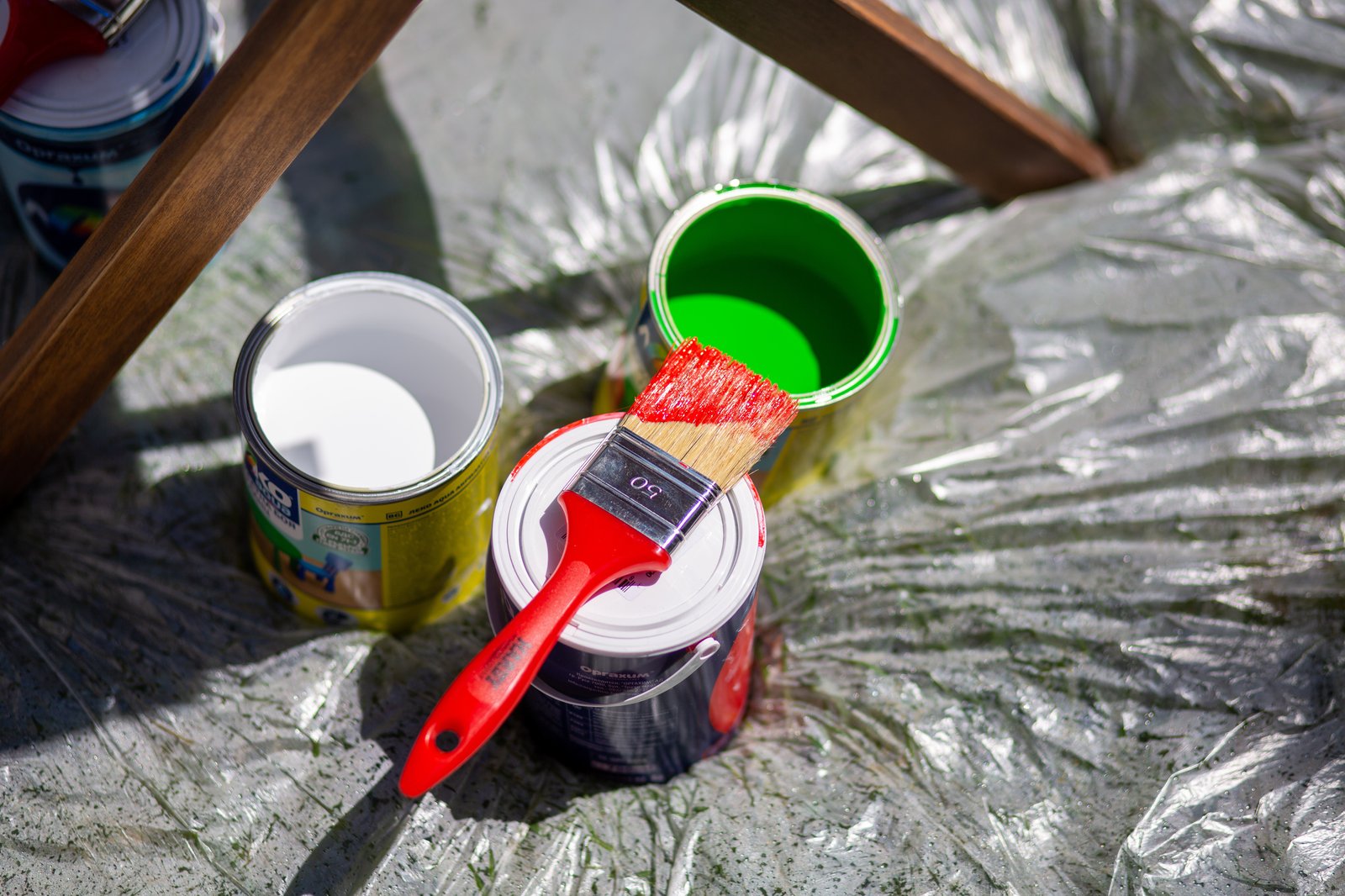 Pinsel und Farbdosen auf einer Abdeckfolie stehen für umweltfreundliche, emissionsarme Anstriche mit natürlichen Materialien.